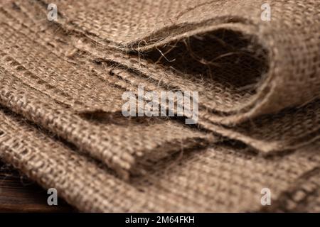 Die ländliche Beschaffenheit des Sacktuchs. Hintergrund aus sehr groben, groben Geweben aus Flachs, Jute oder Hanf. Leinenbeutelmaterial. Konstruktionselement. Abfeuern und Stockfoto