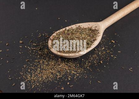 Getrockneter Oregano in Holzlöffel auf dunklem Hintergrund. Stockfoto