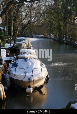 Winter auf den Norfolk Broads, mit schneebedeckten Booten, die in Iced Up Staithe Inlet, Norwich, Norfolk, England, Großbritannien, festgemacht sind Stockfoto
