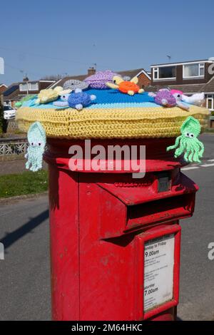 Garn Bombing Stricking auf einem Royal Mail Pillar Box in Residential Street, Norwich, Norfolk, England, Großbritannien Stockfoto