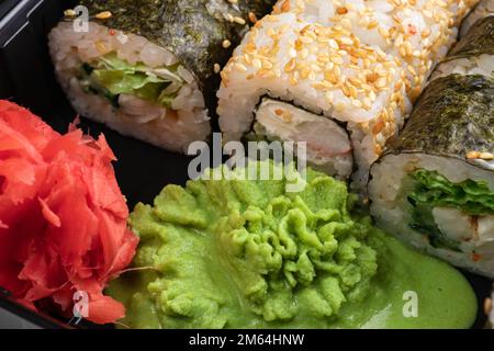 Japanisches Sushi. Maki und Brötchen mit Thunfisch, Lachs, Garnelen, Krabben und Avocado. Blick von oben auf verschiedene Sushi- und All-you-can-eat-Menüs. Regenbogen-Sushi-Brötchen Stockfoto