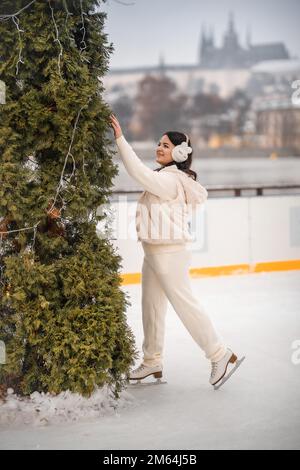 Wunderschönes Mädchen, das Spaß hat, während es auf der Eislaufbahn im Hintergrund der Prager Burg Schlittschuh läuft, Tschechische republik Stockfoto