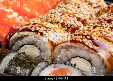 Japanisches Sushi. Maki und Brötchen mit Thunfisch, Lachs, Garnelen, Krabben und Avocado. Blick von oben auf verschiedene Sushi- und All-you-can-eat-Menüs. Regenbogen-Sushi-Brötchen Stockfoto