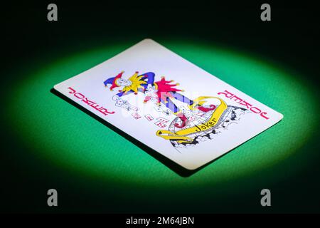 Joker-Karte auf grünem Hintergrund. Joker-Karte in einem Lichtstrahl Stockfoto