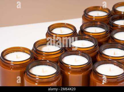 Ein Set mit verschiedenen Aromen Soja-Wachskerzen in braunen Glasgefäßen. Duftkerze zur Beruhigung. Natürliche Kerzen in einem bernsteinfarbenen Glas. Tendy Konzept für heimwerker. Stockfoto