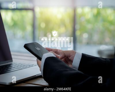 Zwei-Stufen-Authentifizierung (2FA) Konzept. 2023, Code der Shield- und Sternchensymbole, die auf dem Smartphone angezeigt werden, während der Computer zur Validierung des Kennworts verwendet wird Stockfoto