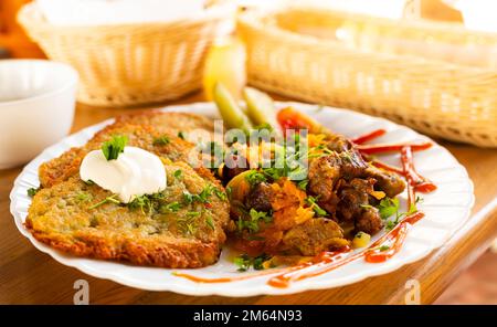 Kartoffelpfannkuchen mit gegrilltem Rindfleisch auf einem weißen Teller Stockfoto