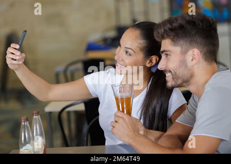 Frau und Mann trinken Bier und machen Selfie im Pub Stockfoto