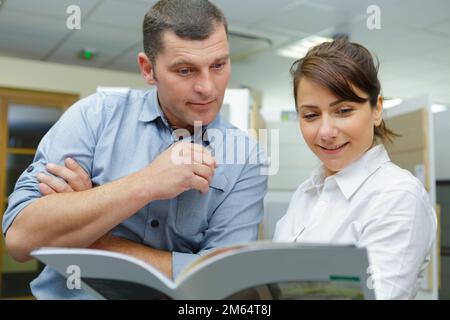 Verkaufsassistent, der sich den Katalog mit dem Kunden ansieht Stockfoto