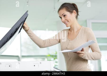 Glückliche Lehrerin, die Arbeitsblätter für ihre nächste Lektion ausdruckt Stockfoto