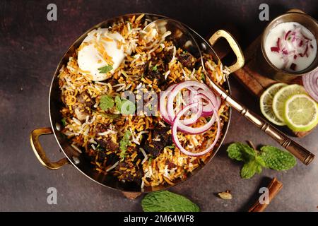 Hausgemachter Ziegenbraten-Biryani | Mutton dum Biryani serviert mit Joghurt-Rita, selektiv im Fokus Stockfoto