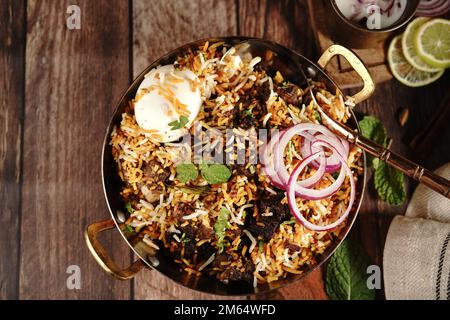 Hausgemachter Ziegenbraten-Biryani | Mutton dum Biryani serviert mit Joghurt-Rita, selektiv im Fokus Stockfoto