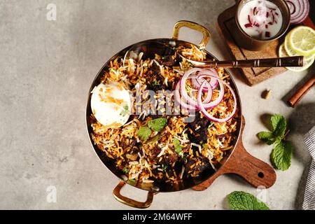 Hausgemachter Ziegenbraten-Biryani | Mutton dum Biryani serviert mit Joghurt-Rita, selektiv im Fokus Stockfoto