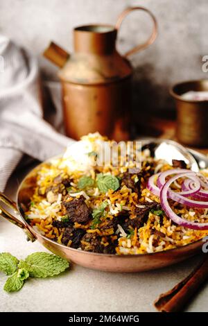 Hausgemachter Ziegenbraten-Biryani | Mutton dum Biryani serviert mit Joghurt-Rita, selektiv im Fokus Stockfoto