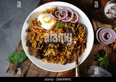 Hausgemachter Ziegenbraten-Biryani | Mutton dum Biryani serviert mit Joghurt-Rita, selektiv im Fokus Stockfoto