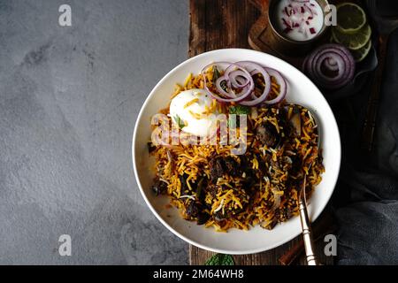 Hausgemachter Ziegenbraten-Biryani | Mutton dum Biryani serviert mit Joghurt-Rita, selektiv im Fokus Stockfoto