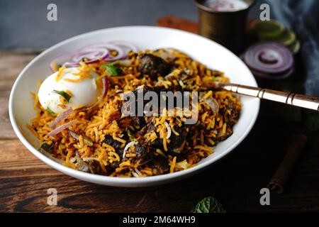 Hausgemachter Ziegenbraten-Biryani | Mutton dum Biryani serviert mit Joghurt-Rita, selektiv im Fokus Stockfoto