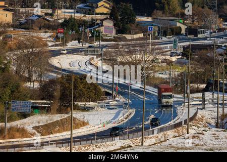Sekigahara, Japan - 25. Dezember 2022: Frachtwaggon auf einer windigen Straße durch verschneite Landschaft an sonnigen Tagen Stockfoto