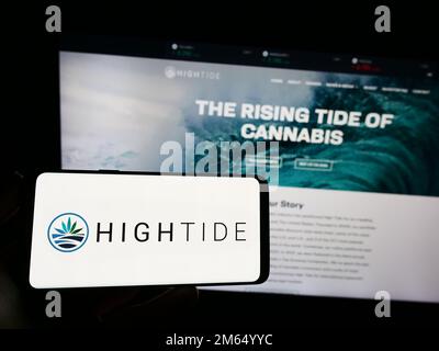 Person, die ein Smartphone mit dem Logo des kanadischen Cannabisunternehmens High Tide Inc. Auf dem Bildschirm vor der Website hält. Konzentrieren Sie sich auf das Display des Telefons. Stockfoto