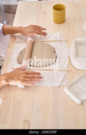 Frau knete Ton in einer Töpferwerkstatt. Eine Frau, die den Lehm lernt. Handwerksklasse. Stockfoto