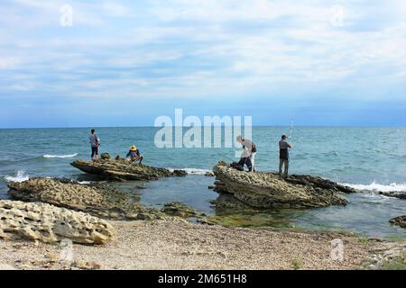 Baku, Aserbaidschan, 09.01.2021. Fischer auf den Felsen fangen Fische im Kaspischen Meer. Stockfoto