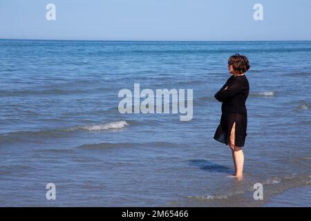 Eine Frau, die das Meer in Gedanken betrachtet Stockfoto