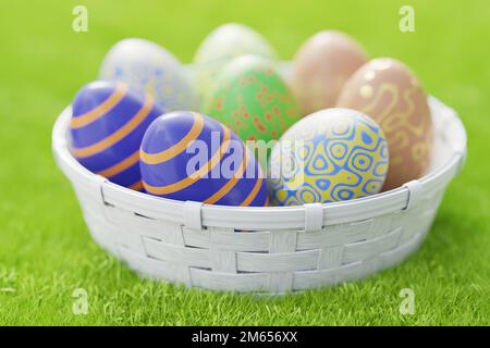 Korb voller bunter Ostereier auf grünem Gras an einem sonnigen Tag. 3D-Rendering.. Stockfoto