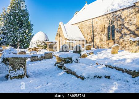 Frühwinterschnee in der St. Michael & All Angels Kirche des 12. Jahrhunderts im Dorf Cotswold in Brimpsfield, Gloucestershire, England Stockfoto