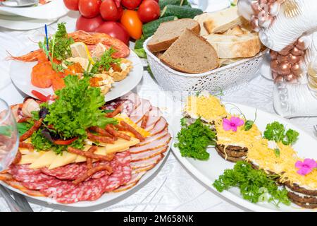 Leckere kalte Snacks sind bereit zum Essen. Eine Auswahl an kalten Snacks auf dem festlichen Tisch. Schneiden Sie Fleisch und Meeresfrüchte auf dem festlichen Tisch. Stockfoto