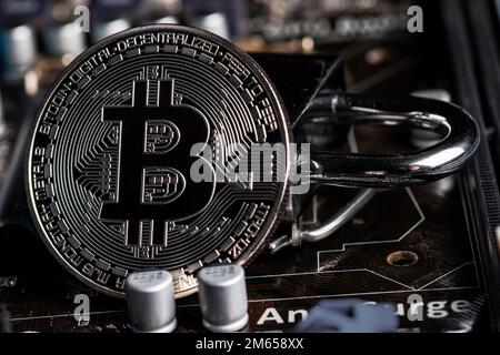 Bitcoin-Sicherheitskonzept. Silberne Bitcoin mit Vorhängeschloss auf der Hauptplatine. Stockfoto