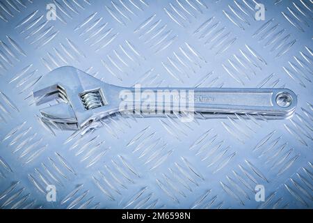 Verstellbarer Schraubenschlüssel auf gerilltem Metallblech-Konstruktionskonzept. Stockfoto