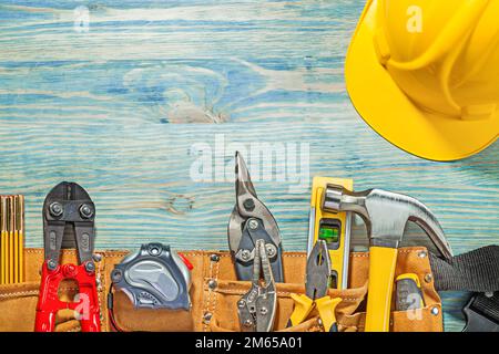 Werkzeuggürtel aus Leder mit Bauwerkzeug auf Holzplatte in horizontaler Ausführung. Stockfoto