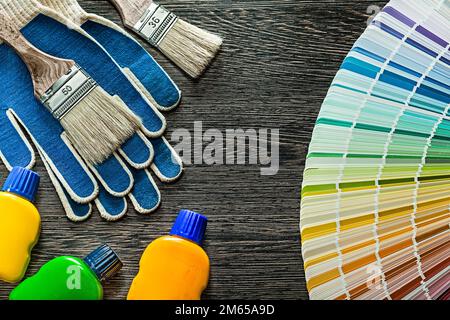 Sicherheitshandschuhe Farbbürsten Flaschen pantone-Lüfter auf Holzbrett. Stockfoto