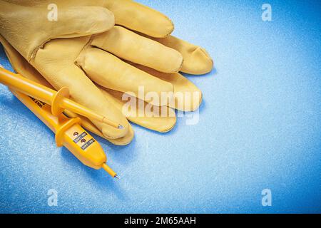 Satz Schutzhandschuhe Elektrotester auf blauem Hintergrund Stromkonzept. Stockfoto