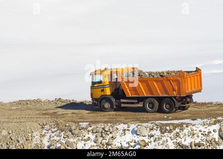 Flurförderzeug mit Anhänger, der mit Steinen und Schutt beladen ist, auf einer Baustelle im Straßenbau, im Winter auf dem Zlatibor Berg i mit Schnee bedeckt Stockfoto