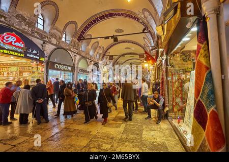 ISTANBUL, ISTANBUL - 21. APRIL 2017: Einkaufsbummel im Großen Basar, handgefertigte Kissen, Taschen und Teppiche stehen an der Wand zum Verkauf. Die Sonnenlicht-Com Stockfoto