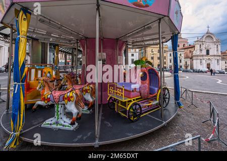 Fahrgeschäfte für Kinder auf der Piazza Duomo in L'Aquila. Im Hintergrund wurde die Kirche Santa Maria del Suffragio nach dem Erdbeben restauriert. Abruzzen Stockfoto