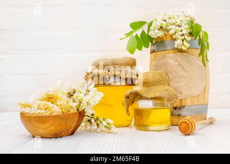 Ernte 2023. Honig in Waben, ein Holzfass und Wachs mit umweltfreundlichem Akaziennektar, Glasgläser gefüllt mit Bienenzucht Stockfoto