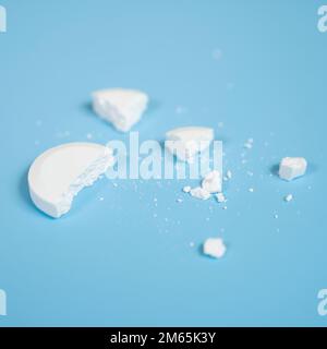 Eine zerdrückte Medizinpille auf einer blauen Oberfläche Stockfoto