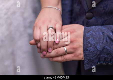 Nahaufnahme der Hände eines frisch verheirateten Paares mit Eheringen. Stockfoto