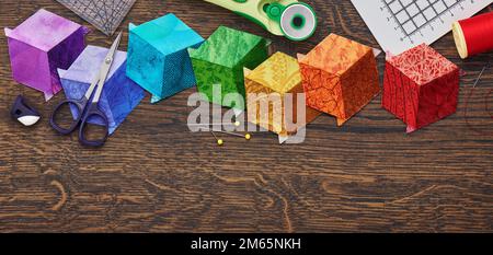 Diamanten in Form eines Würfels in den Farben Regenbogen, Steppdecken und Nähzubehör genäht. Platz für Text. Stockfoto