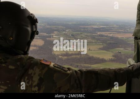 Sgt. 1. Class Kyle Moyer, ein UH-60m Black Hawk Helikopter Crew Chief und ein Lehrer am Eastern Army National Guard Aviation Training Site (EAATS), schaut auf einen anderen Hubschrauber, der auch am 5. April Wassereimer-Training in Fort Indiantown Gap absolviert. Diese gemeinsame Schulung der EAATS und der Feuerwehrleute für Naturschutz verbessert ihre Fähigkeit, Wassereimer als Ressource für Waldbrände oder vorgeschriebene Verbrennungen zu verwenden. Stockfoto