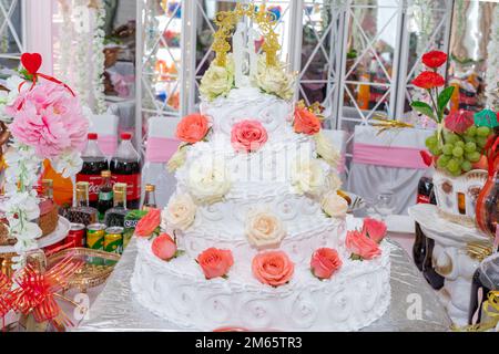 Hochzeitstorte mit Figuren von Frischvermählten und roten Rosen, Nahaufnahme Stockfoto