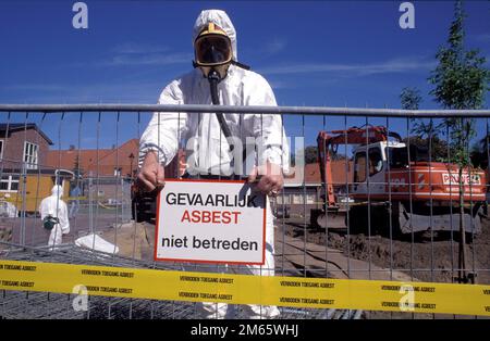 Niederlande, Arnheim, in einer alten Nachbarschaft wird Asbest entfernt. Ein Arbeiter hängt ein Schild mit der Aufschrift „Zutritt verboten“ am Zaun auf Stockfoto