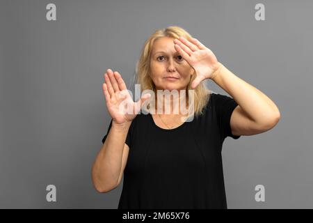 Die wunderschöne blonde weiße Frau hält ihre Hände vor sich, mit offenen Handflächen, die in die Kamera zeigen. Werbekonzept der Geschäftsführerin Stockfoto