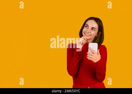 Aufgeregte brünette Frau, die die neueste mobile App per Telefon überprüft Stockfoto
