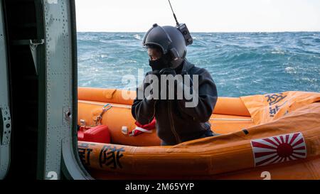 Ein Rettungsschwimmer der japanischen Seeschifffahrts-Selbstverteidigungstruppe bereitet sich auf den Betrieb eines motorisierten Floßes vor, das von einem ShinMaywa US-2, das der JMSDF-Luftpatrouille 71 zugeteilt wurde, während eines Trainingsflugs vor der Küste der Marine Corps Air Station Iwakuni, Japan, am 5. April 2022 eingesetzt wurde. USA Sondereinsätze und die Fähigkeit der japanischen Selbstverteidigungskräfte, zusammenzuarbeiten und dabei Fähigkeiten wie die amphibische Luftwaffe der US-2 zu nutzen, sind für die Bereitstellung von Rettungs- und humanitären Hilfsmaßnahmen in einer von Wasser bedeckten Region und auf Inseln in Randlage von entscheidender Bedeutung. Stockfoto