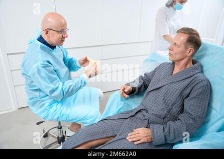Ruhiger Patient und professioneller Arzt, der sich vor Beginn der Behandlung unterhält Stockfoto