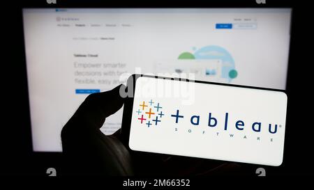 Person, die ein Mobiltelefon mit dem Logo des amerikanischen Unternehmens Tableau Software Inc. Auf dem Bildschirm vor der geschäftlichen Webseite hält. Konzentrieren Sie sich auf das Display des Telefons. Stockfoto