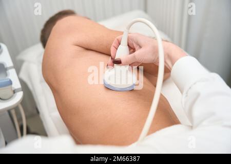 Uzist führt eine umfassende Untersuchung mit einem Ultraschallgerät durch Stockfoto